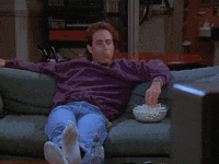 a man is sitting on a couch with a bowl of popcorn