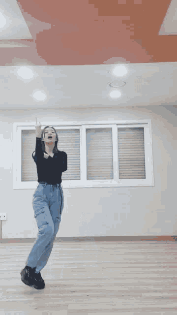 a woman is dancing in a room with a window