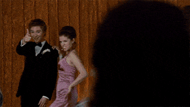 a man in a suit and tie stands next to a woman in a dress