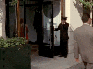 a man in a suit opens a door for a woman in a red dress