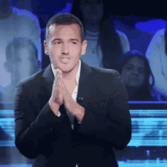 a man in a suit is clapping his hands in a crowd