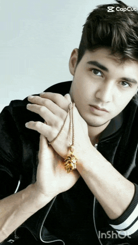 a young man is holding a necklace with a pine cone pendant on it
