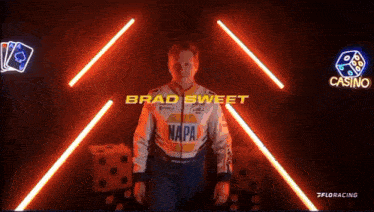 a man in a napa jacket is standing in a dark room with neon lights .