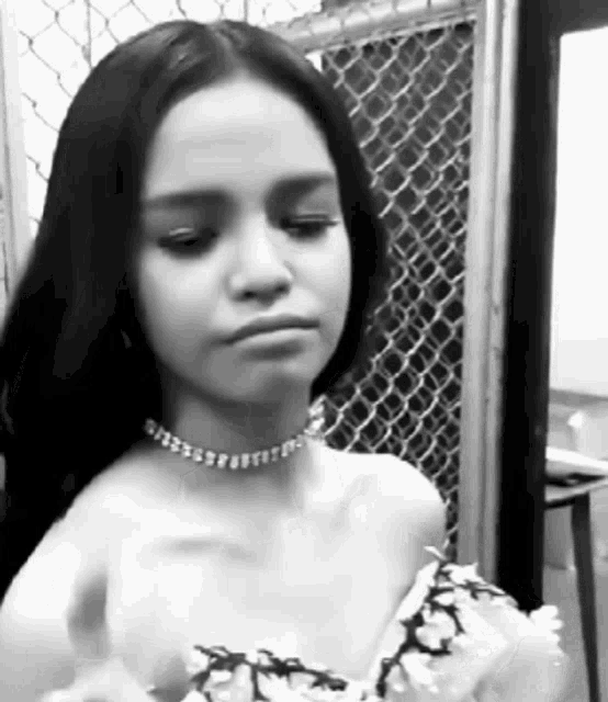 a black and white photo of a young girl wearing a choker necklace .