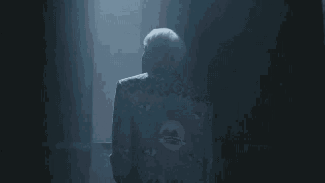 a man in a suit is standing in a dark room in a dark room .