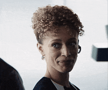 a woman with curly hair wearing a headset smiles