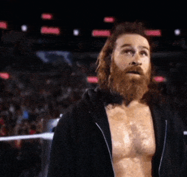 a man with a beard wearing a black hoodie is standing in front of a crowd