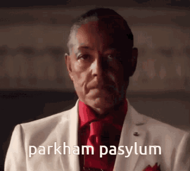 a man in a white suit and red tie has parkham pasylum written on his chest