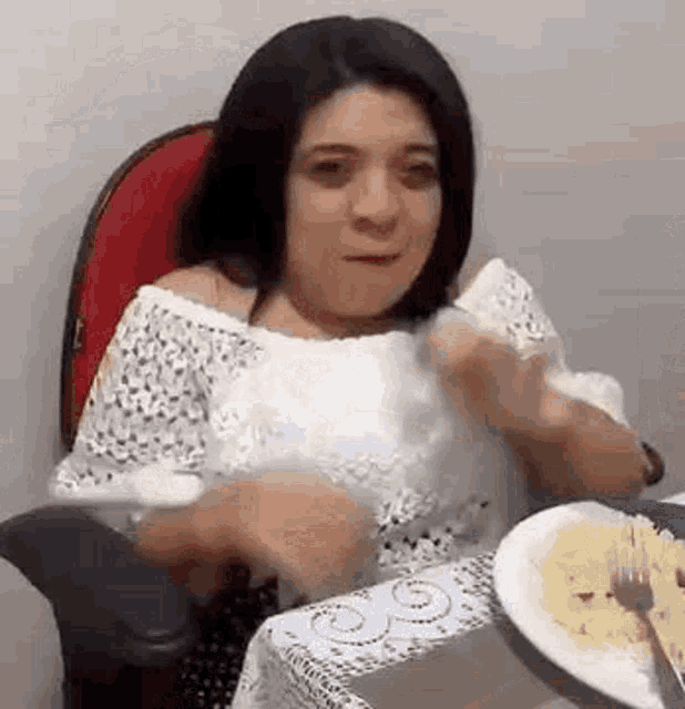 a woman is sitting at a table eating food with a fork .