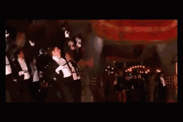 a group of people are dancing in a dark room .