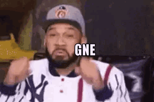 a man with a beard is wearing a hat and giving a thumbs up sign .