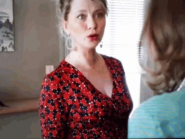 a woman in a red and black polka dot dress talks to another woman