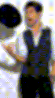 a blurry picture of a man wearing a vest and a white shirt holding a pair of scissors .