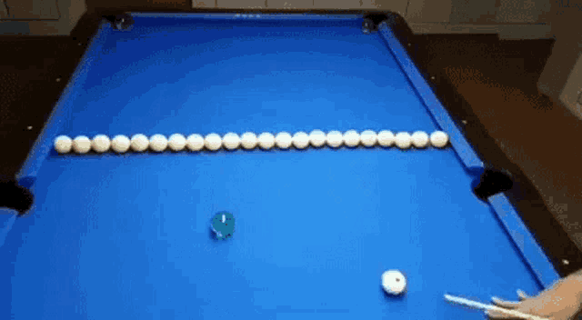 a pool table with balls on it and a person holding a pool cue .