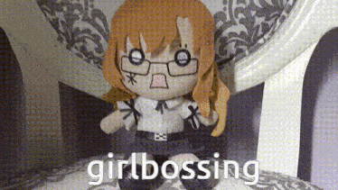 a stuffed doll with glasses is sitting on a chair with the words girlbossing written below it