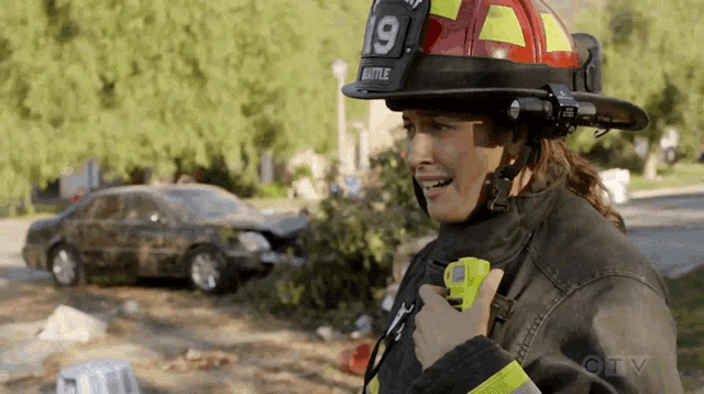 a firefighter with the number 19 on her helmet is talking on a walkie talkie