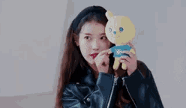 a young woman in a leather jacket is holding a stuffed animal .