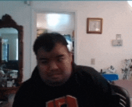 a man wearing a black shirt with the letter s on it looks at the camera