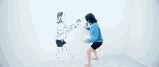 a woman in a blue sweatshirt is standing in front of a drawing of a woman