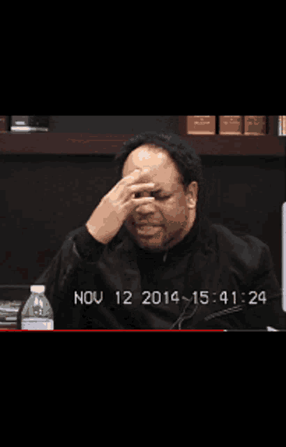 a man sits at a desk with a bottle of water in front of him and the date nov 12 2014