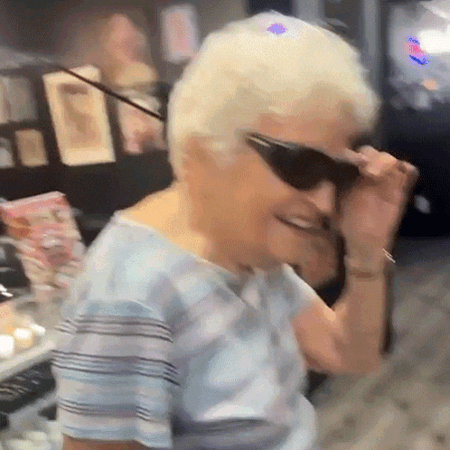 an elderly woman wearing sunglasses and a blue shirt