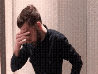 a man is covering his face with his hand .