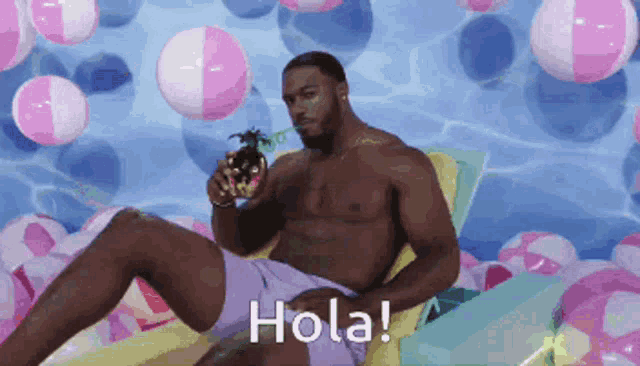 a shirtless man is sitting on a beach chair holding a pineapple and the words hola on the bottom