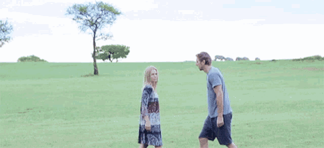 a man and a woman are standing in a grassy field .