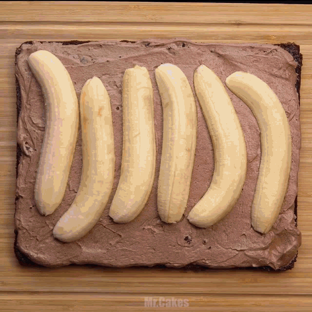 sliced bananas on top of a chocolate frosting on a cutting board with mr.cakes written on the bottom