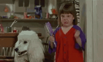 a little girl is brushing her hair next to a white poodle