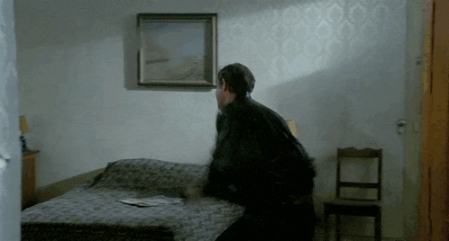 a man sitting on a bed in a room with a picture on the wall