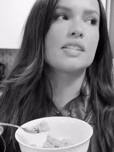a woman is eating a bowl of cereal with a spoon in it