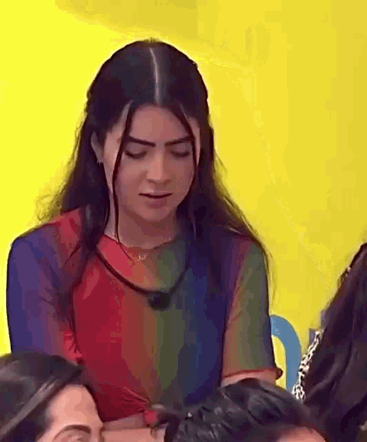 a woman with long hair is sitting in front of a yellow wall .