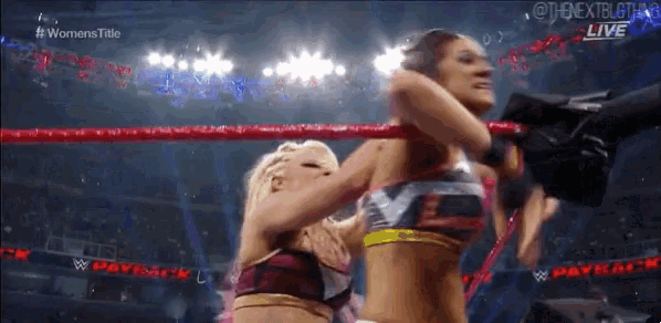 two women are wrestling in a ring and one of them is holding the other 's head .
