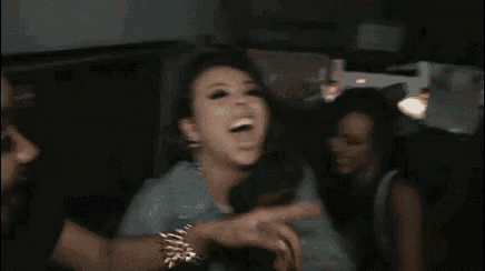 two women are sitting in a car laughing and making funny faces .