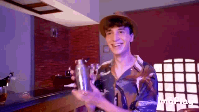 a man in a hat is holding a shaker in his hand .