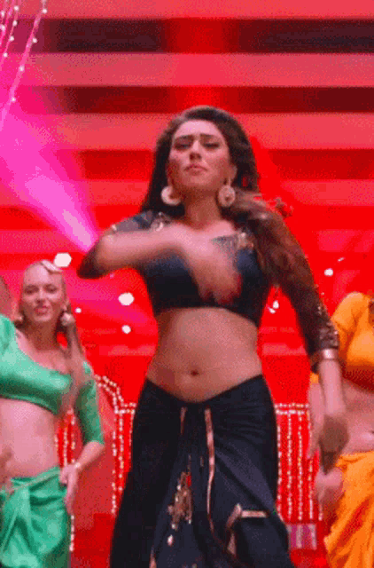 a woman in a crop top is dancing on a stage with other women