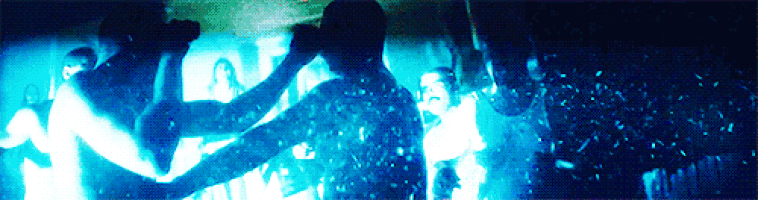 a group of people are dancing in a dark room with a blue light behind them that says ' i love you ' on it
