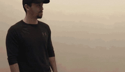 a man wearing a black under armour shirt and a baseball cap .