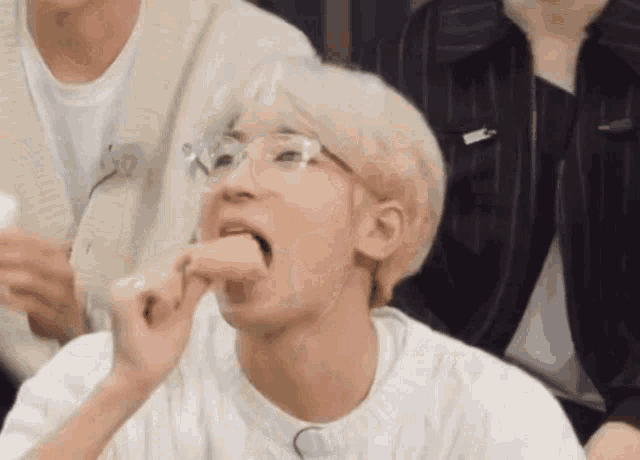 a young man with glasses is eating a piece of food .
