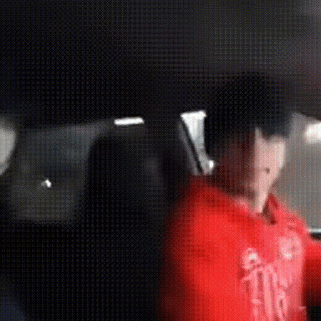 a man in a red hoodie is sitting in the back of a car