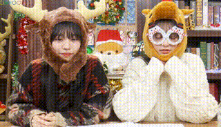 two girls are sitting at a table wearing christmas costumes .