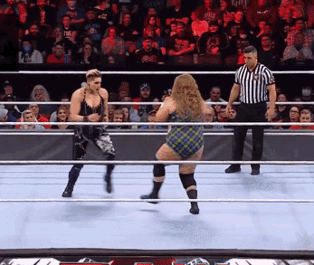 two women are wrestling in a ring with a referee standing behind them