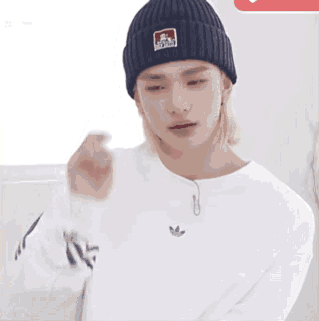 a young man wearing a beanie and a white adidas sweater