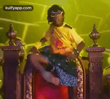 a man in a yellow shirt is sitting on a throne with a woman .