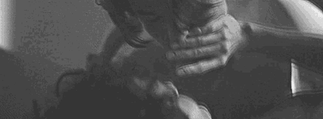 a black and white photo of a man licking another man 's face .