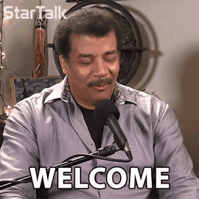 a man sitting in front of a microphone with the word welcome written on his face