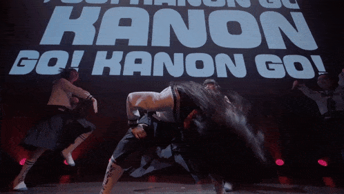 a group of girls are dancing in front of a large sign that says " go kanon go "