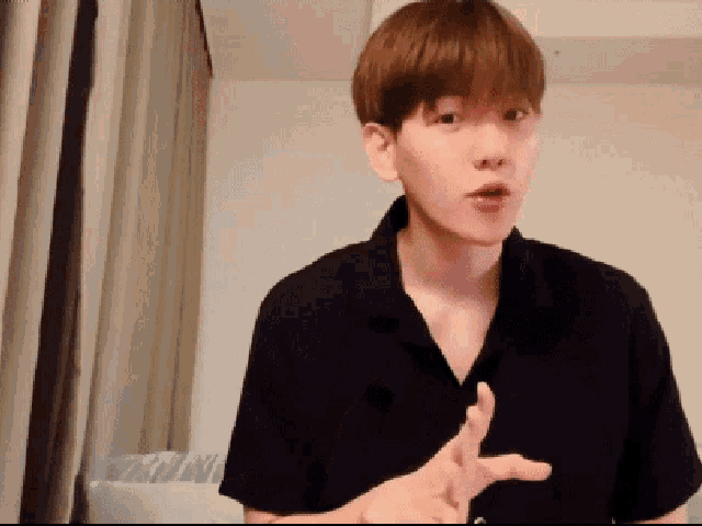 a man wearing a black shirt is making a gesture with his hands
