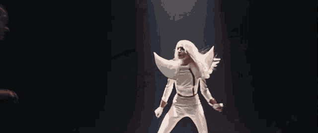 a woman in a white costume is standing in the dark